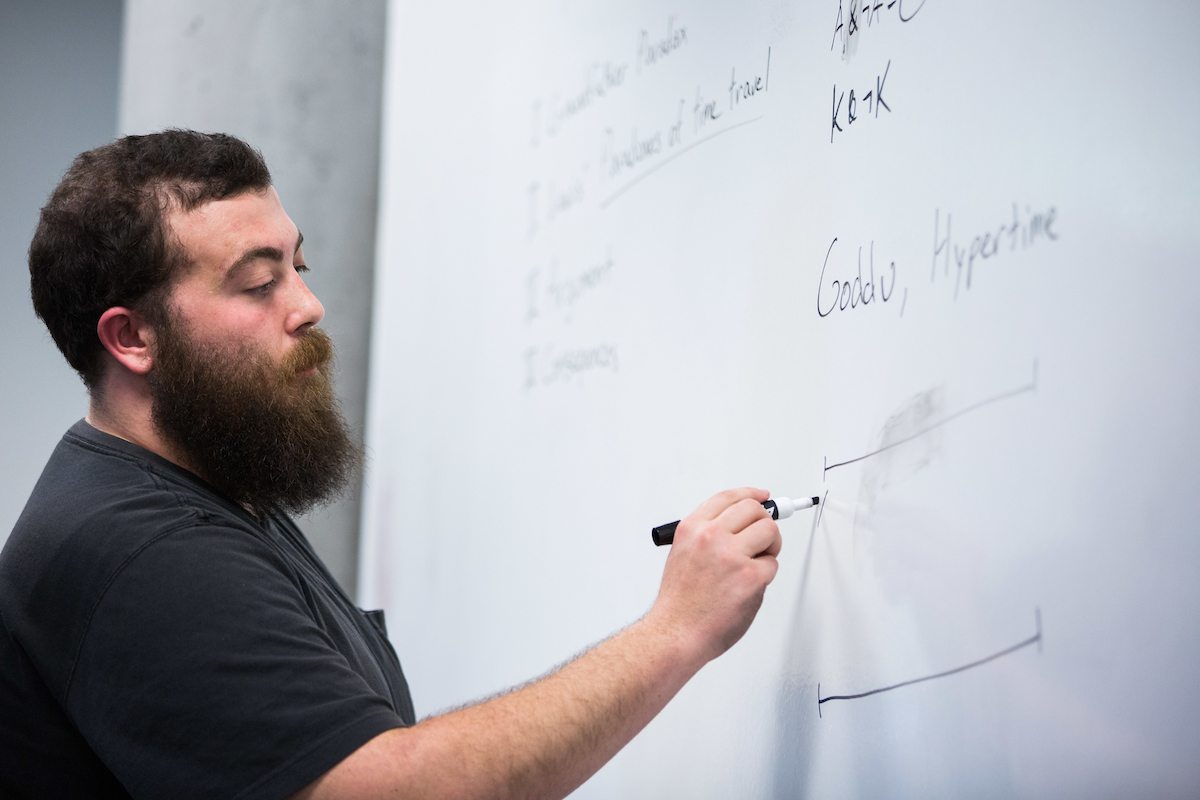 A student writes on a board. 