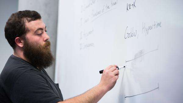 A student writes on a whiteboard at a Philosophy club meeting.